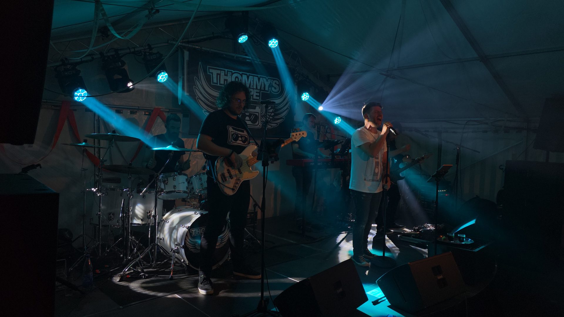 Band auf der Bühne im Festzelt, Sänger und Gitarrist in blauem Licht