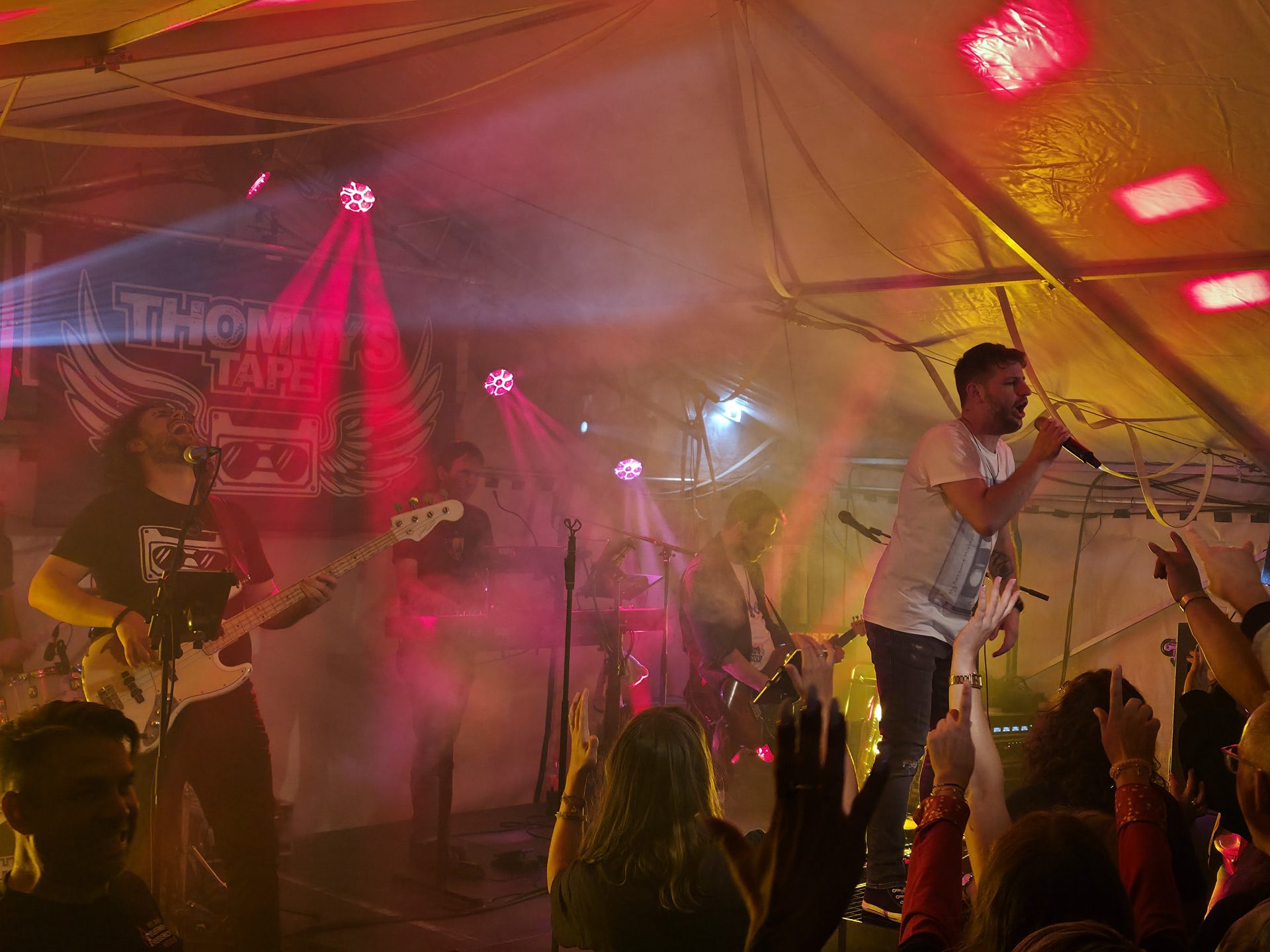 Band spielt im Festzelt, das Publikum hat die Arme erhoben