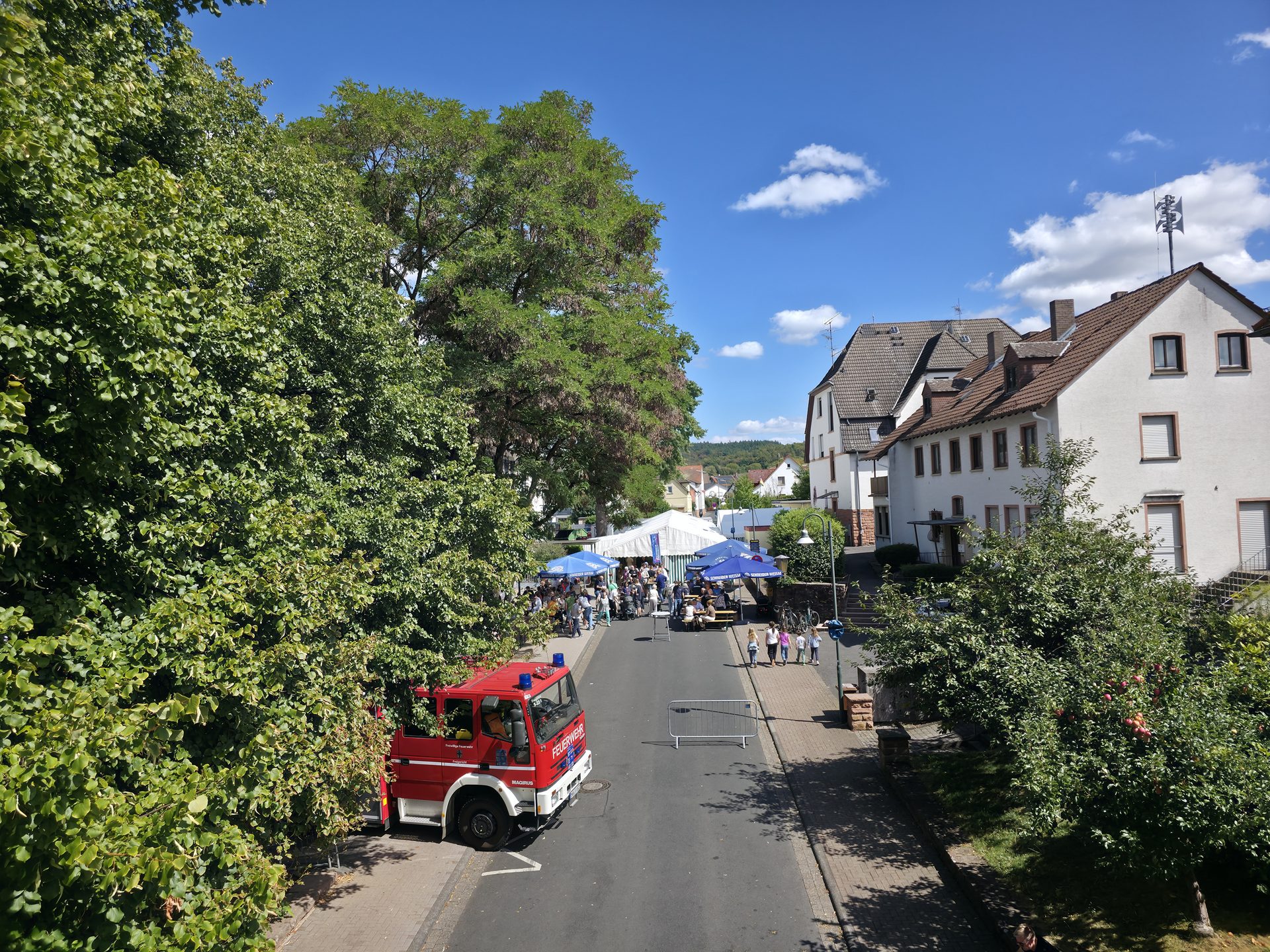 Festmeile mit Löschfahrzeug, Zelten und Besuchern bei Sonnenschein