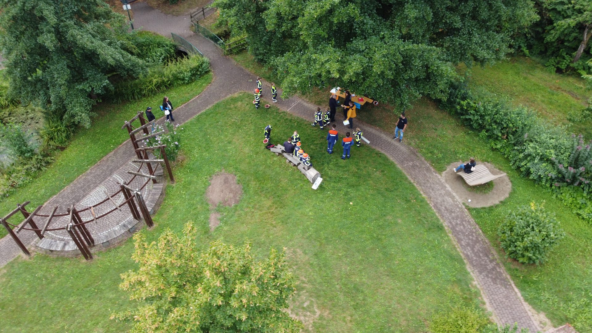 Drohnenaufnahme: Gruppen der Jugendfeuerwehr an einer Wettkampfstation im Park